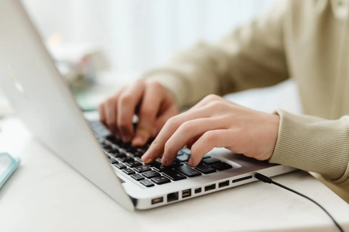 Hands of a woman typing on a laptop. The image illustrates the subject: "How to optimize website structure to improve rankings."