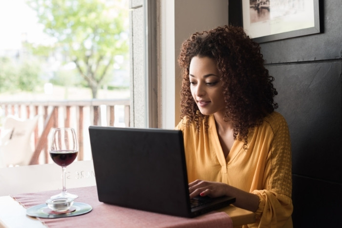 A woman smiles while looking at her laptop. The image represents the importance of writing helpful blogs.