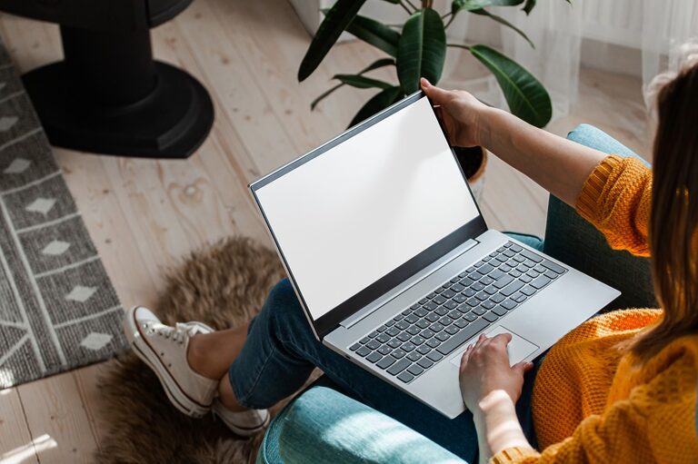 Woman wearing orange clothes working with a laptop in her living room.