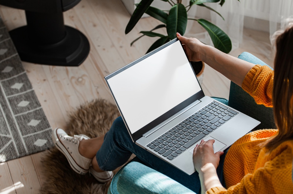 Woman wearing orange clothes working with a laptop in her living room.