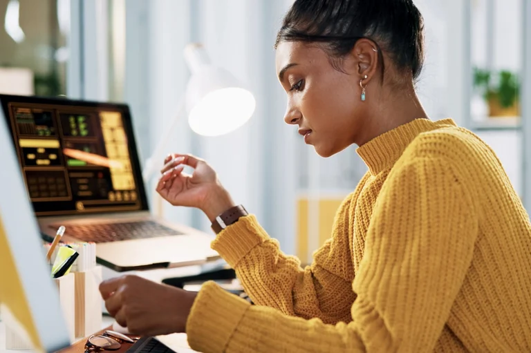 Black woman wearing a yellow sweater while working on her home office.