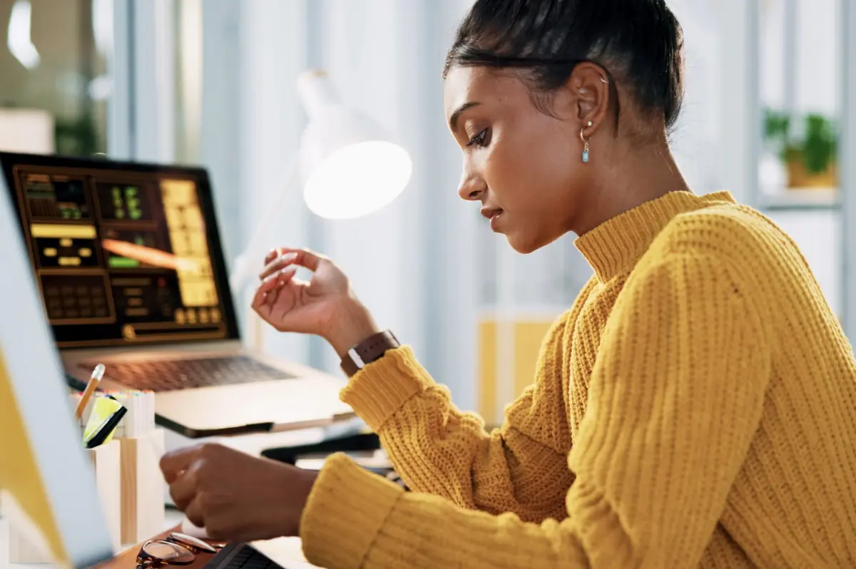 Black woman wearing a yellow sweater while working on her home office.
