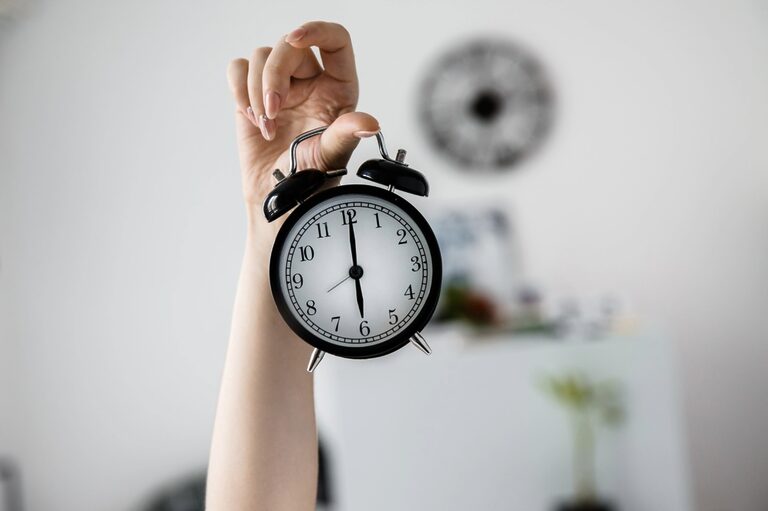 Classic clock being held by the right hand of a woman