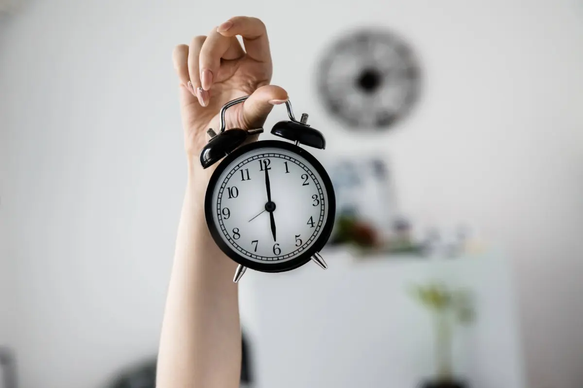 Classic clock being held by the right hand of a woman