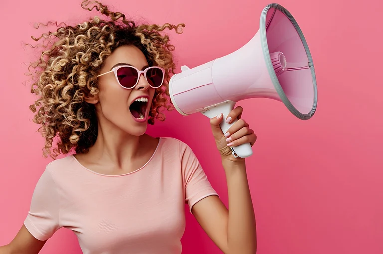 A black woman wearing a pink t-shirt and holding a pink megaphone in a pink background.
