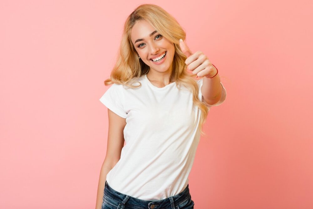 The image shows a blonde model displaying a plain white t-shirt.