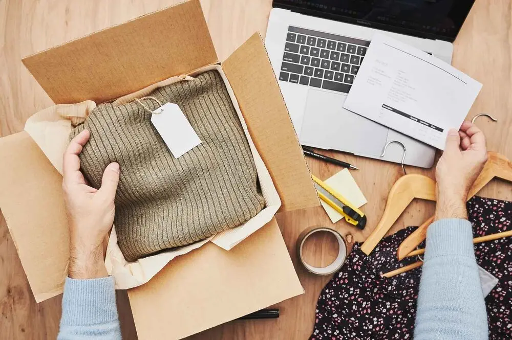 A person wrapping a package and checking shipping details on a computer screen.