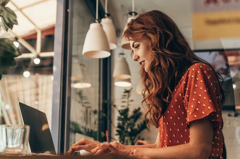 Woman working on her laptop in a cafeteria.