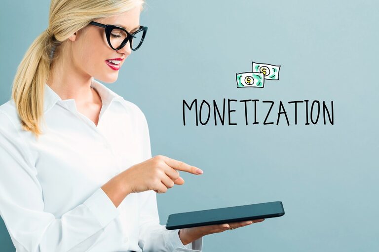 Blonde woman wearing glasses and a white shirt, holding a tablet. The image shows the word "MONETIZATION" besides her.