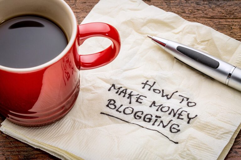 Red mug full of coffee above a napkin with the words "how to make money blogging" written on it.